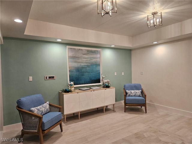 living area featuring light wood-type flooring, a notable chandelier, baseboards, and recessed lighting