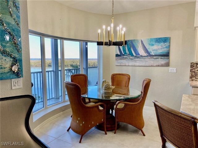 dining space featuring plenty of natural light, an inviting chandelier, a water view, and light tile patterned flooring