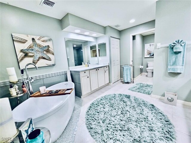 bathroom with toilet, vanity, tile patterned floors, and a bathtub