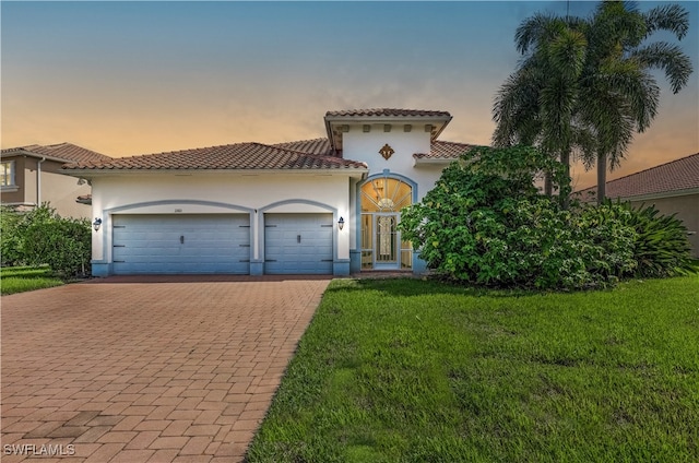 mediterranean / spanish home featuring a yard and a garage