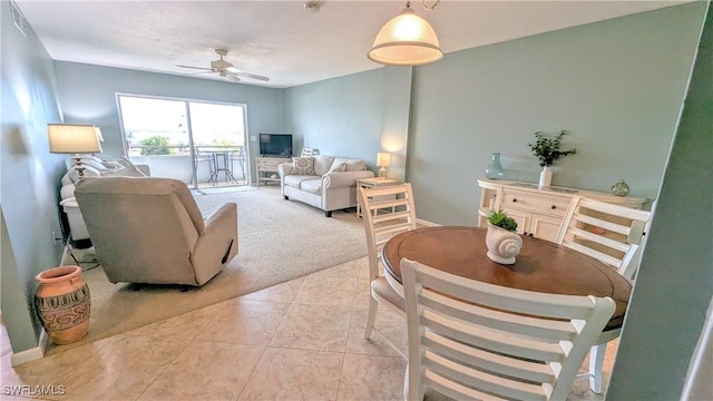 living area with a ceiling fan, light carpet, and light tile patterned floors