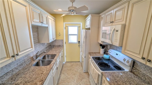 kitchen with white appliances, a sink, cream cabinetry, and light stone countertops