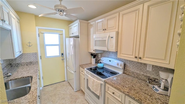 kitchen with light stone counters, white appliances, a sink, and light tile patterned floors