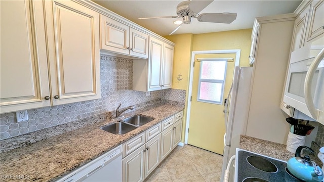 kitchen featuring white appliances, decorative backsplash, light stone countertops, a sink, and light tile patterned flooring