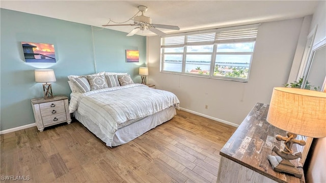 bedroom featuring ceiling fan, baseboards, and wood finished floors