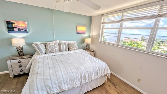 bedroom featuring a ceiling fan, baseboards, and wood finished floors