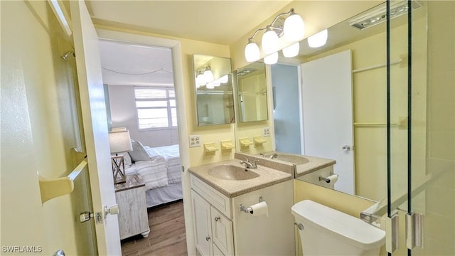 ensuite bathroom featuring toilet, a shower with door, ensuite bath, wood finished floors, and vanity