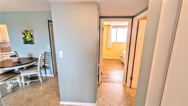 corridor featuring light tile patterned floors and baseboards