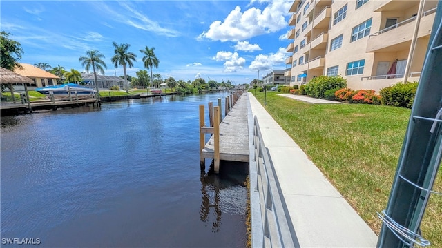 view of dock with a water view and a yard