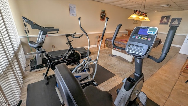 workout area with visible vents, tile patterned flooring, a paneled ceiling, and baseboards