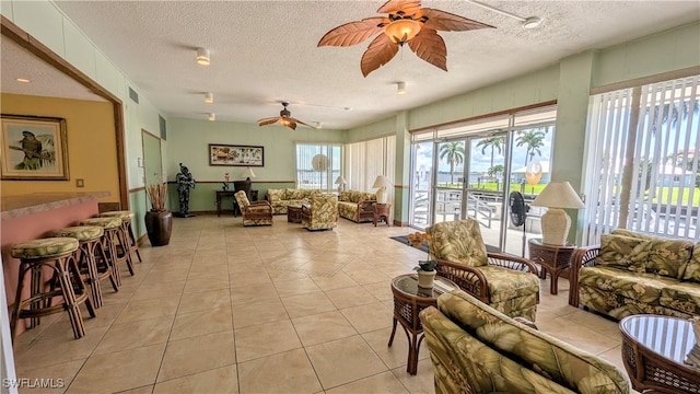 living area with a ceiling fan, visible vents, a textured ceiling, and light tile patterned floors