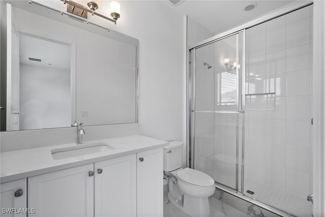 bathroom featuring vanity, toilet, and a shower with door