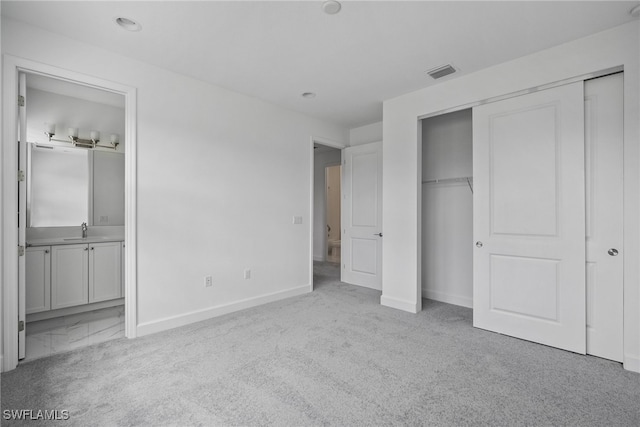 unfurnished bedroom with light colored carpet, sink, and connected bathroom