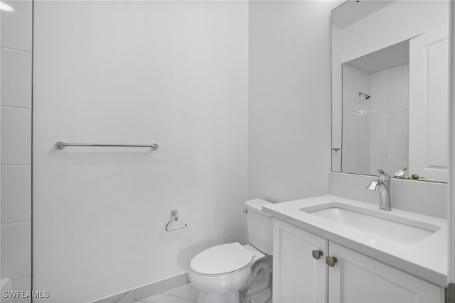 bathroom featuring vanity, toilet, and a tile shower