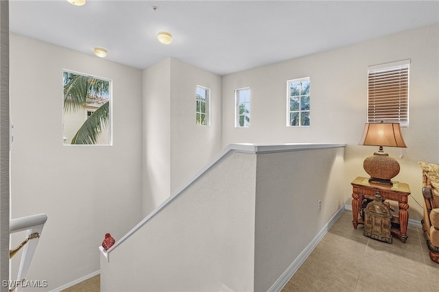 hallway with an upstairs landing, tile patterned flooring, and baseboards