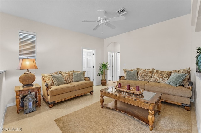 living room with light tile patterned floors, baseboards, visible vents, arched walkways, and ceiling fan