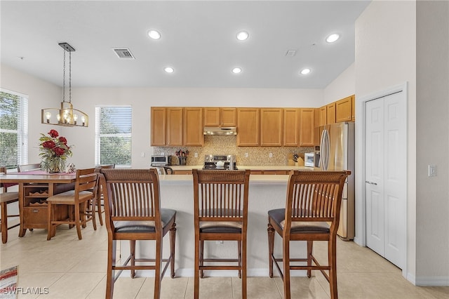 kitchen with a kitchen bar, stainless steel appliances, hanging light fixtures, a chandelier, and light tile patterned flooring