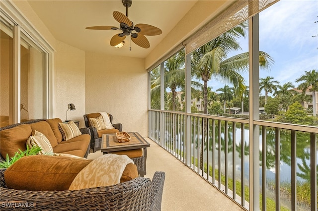 balcony with an outdoor living space, a ceiling fan, and a water view