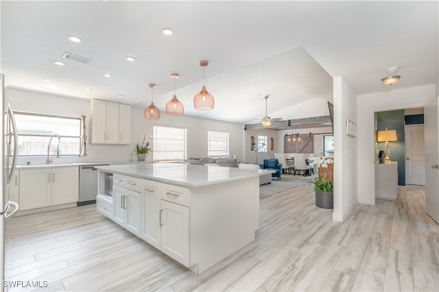 kitchen featuring vaulted ceiling, appliances with stainless steel finishes, light hardwood / wood-style floors, ceiling fan, and white cabinets