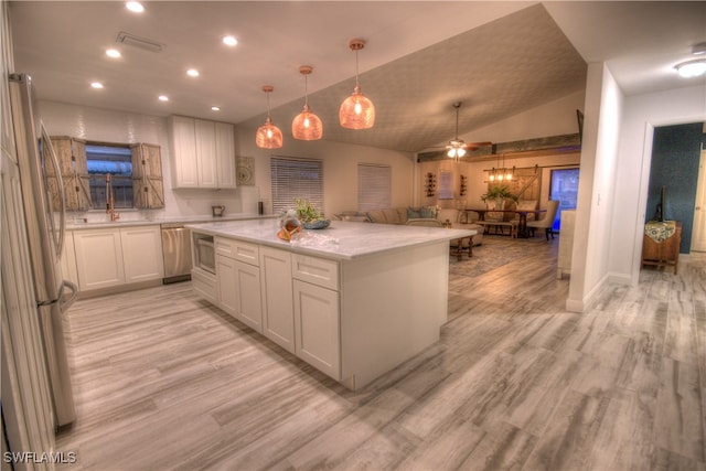 kitchen featuring stainless steel appliances, ceiling fan, lofted ceiling, a barn door, and light hardwood / wood-style floors