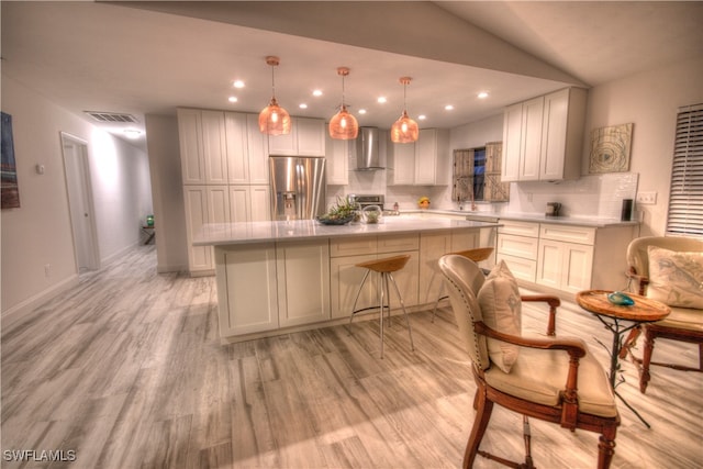 kitchen featuring light hardwood / wood-style flooring, a kitchen island, appliances with stainless steel finishes, lofted ceiling, and a breakfast bar area