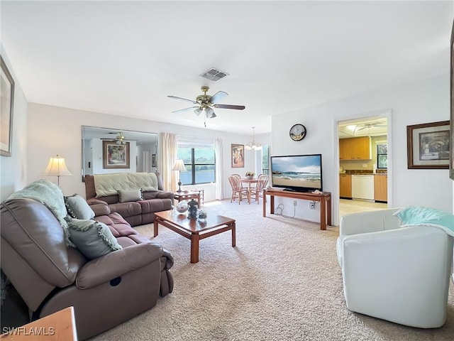 carpeted living room featuring ceiling fan with notable chandelier