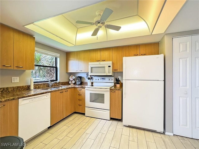 kitchen with ceiling fan, sink, light hardwood / wood-style flooring, dark stone countertops, and white appliances