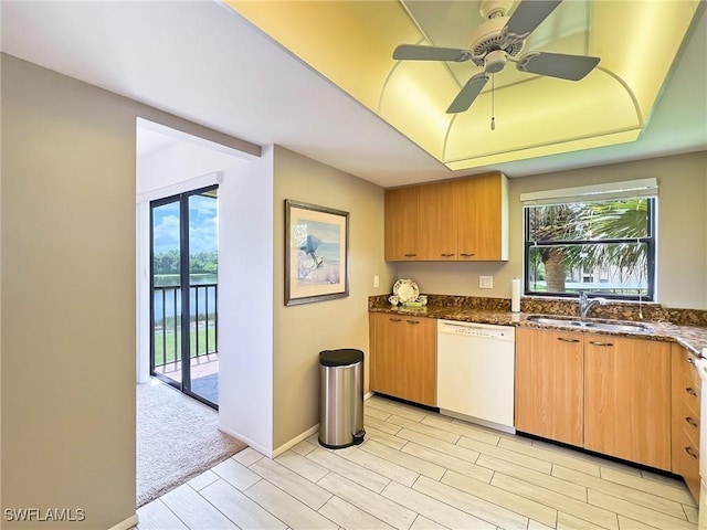 kitchen featuring ceiling fan, dishwasher, sink, dark stone counters, and light carpet