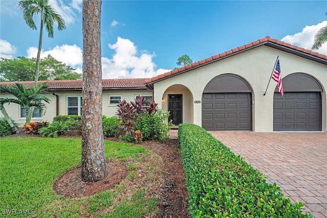 mediterranean / spanish house featuring a front yard and a garage