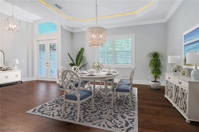 dining area with dark wood-type flooring, crown molding, a raised ceiling, and a chandelier