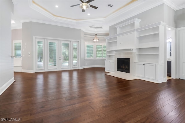 unfurnished living room with dark wood-type flooring, ceiling fan, ornamental molding, and a tray ceiling