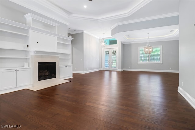 unfurnished living room featuring ornamental molding, dark wood-type flooring, a tray ceiling, and french doors