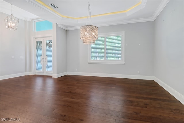 empty room with crown molding, a notable chandelier, a tray ceiling, and dark hardwood / wood-style flooring