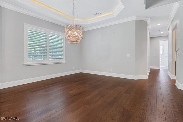 unfurnished room featuring ornamental molding, a chandelier, a tray ceiling, and dark hardwood / wood-style flooring