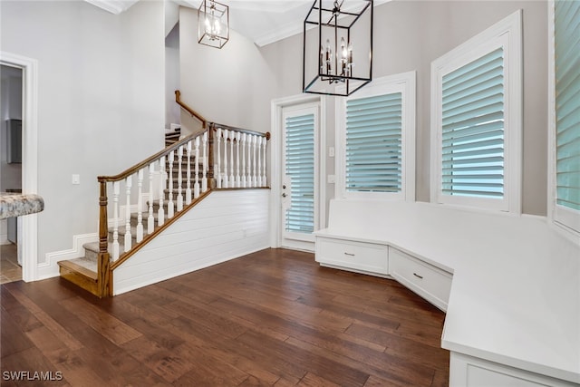 entrance foyer featuring an inviting chandelier, crown molding, and dark hardwood / wood-style flooring