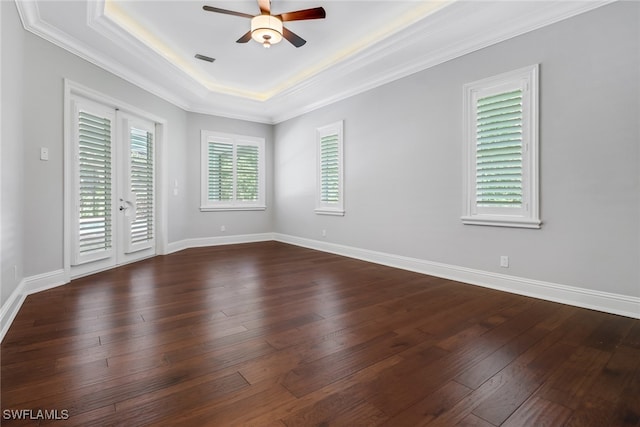 unfurnished room with dark wood-type flooring, ceiling fan, a raised ceiling, and crown molding