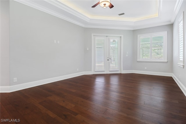 empty room with french doors, ornamental molding, a tray ceiling, and dark hardwood / wood-style floors