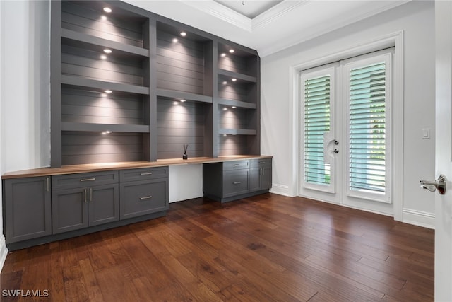 unfurnished office featuring ornamental molding, built in desk, and dark hardwood / wood-style floors