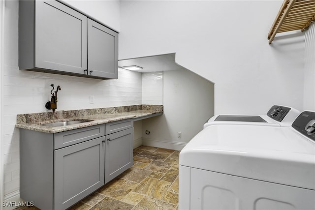 laundry room featuring sink, washing machine and clothes dryer, and cabinets