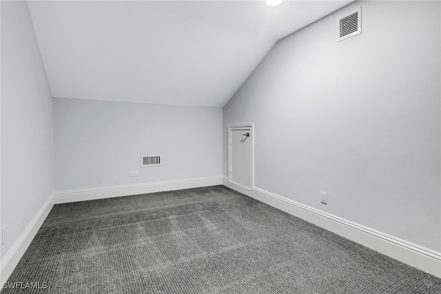 bonus room with dark carpet and vaulted ceiling