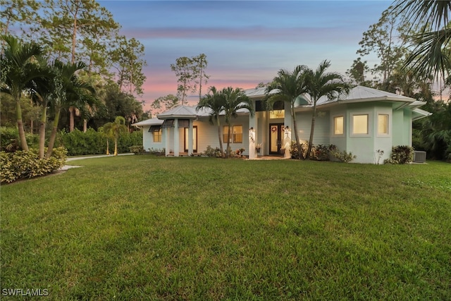 view of front of property featuring central air condition unit and a lawn