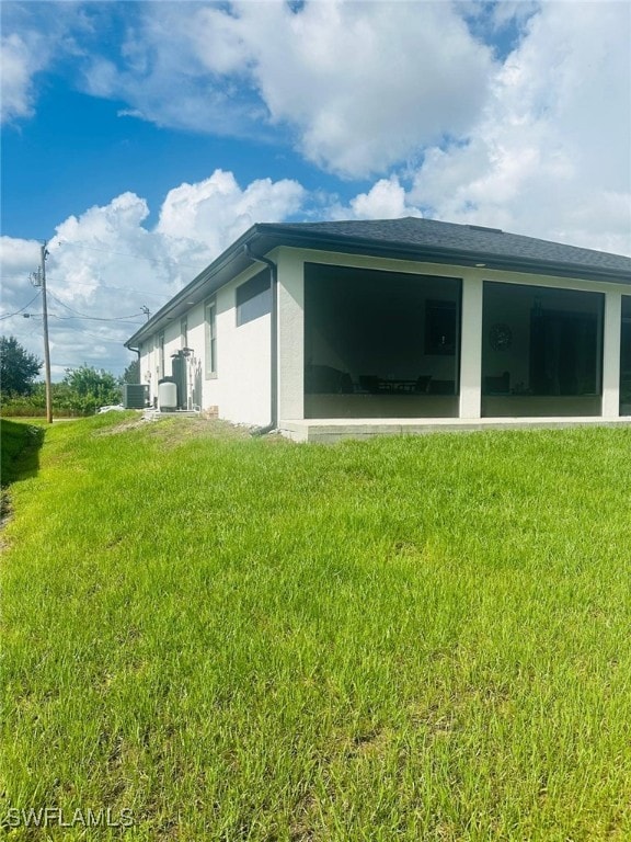 exterior space with a lawn and central AC