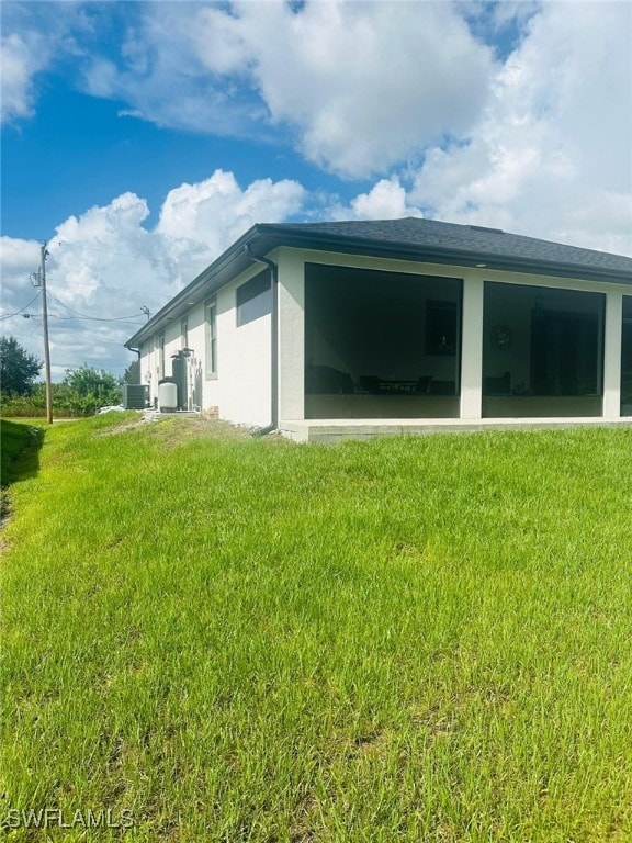 3713 25th St SW, Lehigh Acres, FL 33976 - view of side of property featuring an attached garage, a lawn, central air condition unit, and stucco siding