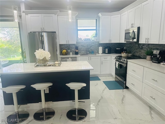 kitchen featuring appliances with stainless steel finishes, a breakfast bar area, sink, and white cabinets