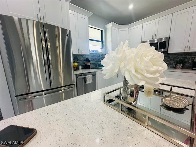 kitchen featuring white cabinetry, stainless steel appliances, and light stone countertops