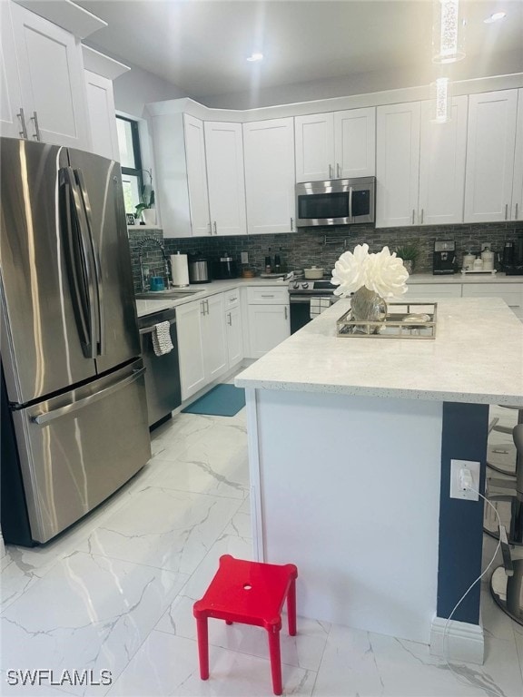 kitchen featuring a center island, stainless steel appliances, decorative backsplash, and white cabinets