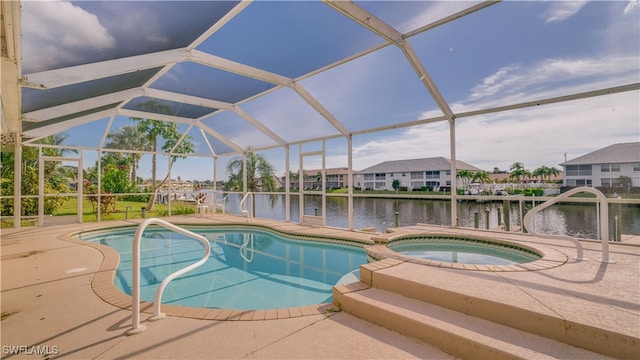 view of pool with glass enclosure, an in ground hot tub, a patio area, and a water view