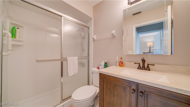 bathroom with a shower with shower door, toilet, and vanity