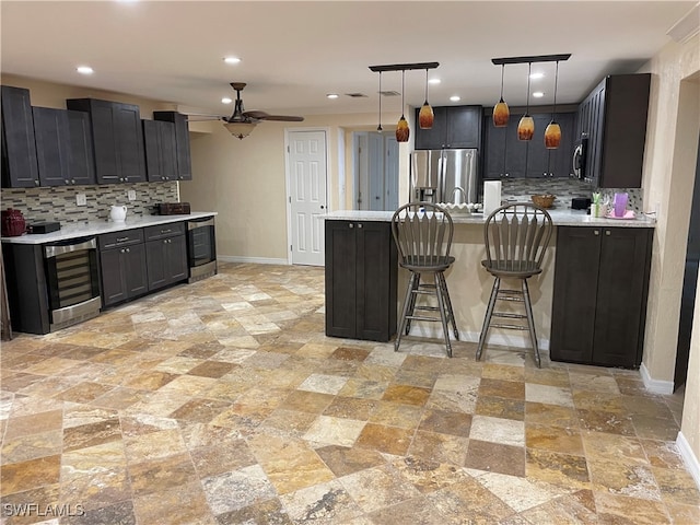 kitchen featuring hanging light fixtures, stainless steel appliances, wine cooler, ceiling fan, and decorative backsplash