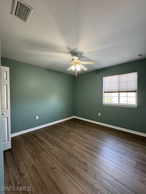 empty room with ceiling fan and dark hardwood / wood-style flooring